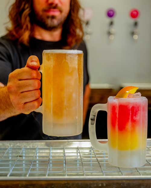 Barman holding a pint of Umbrella London Cider out in front of him