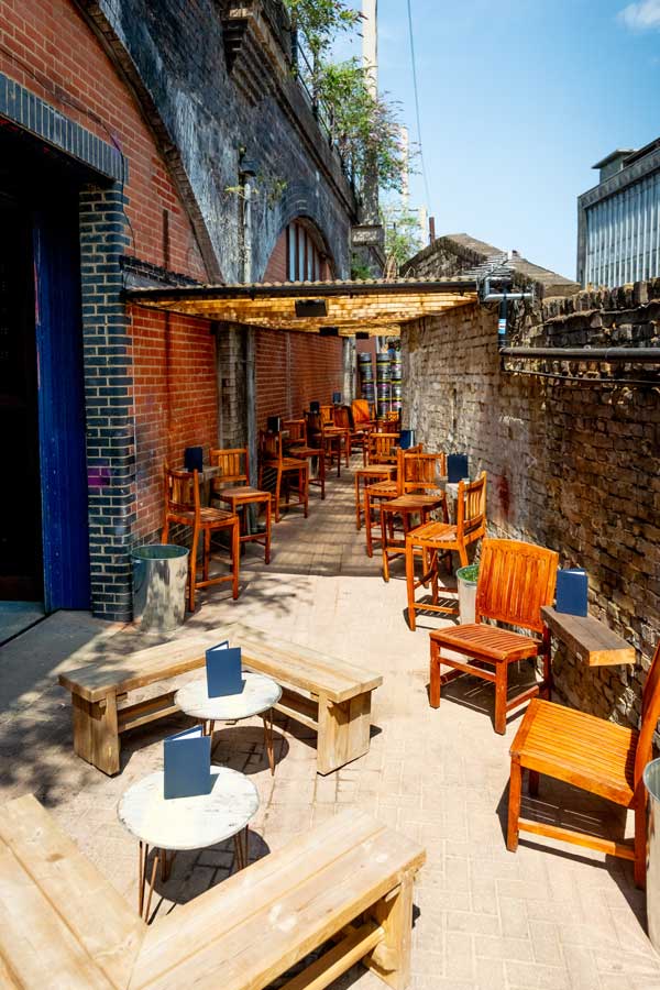 Lots of chairs and tables outside a railway arch